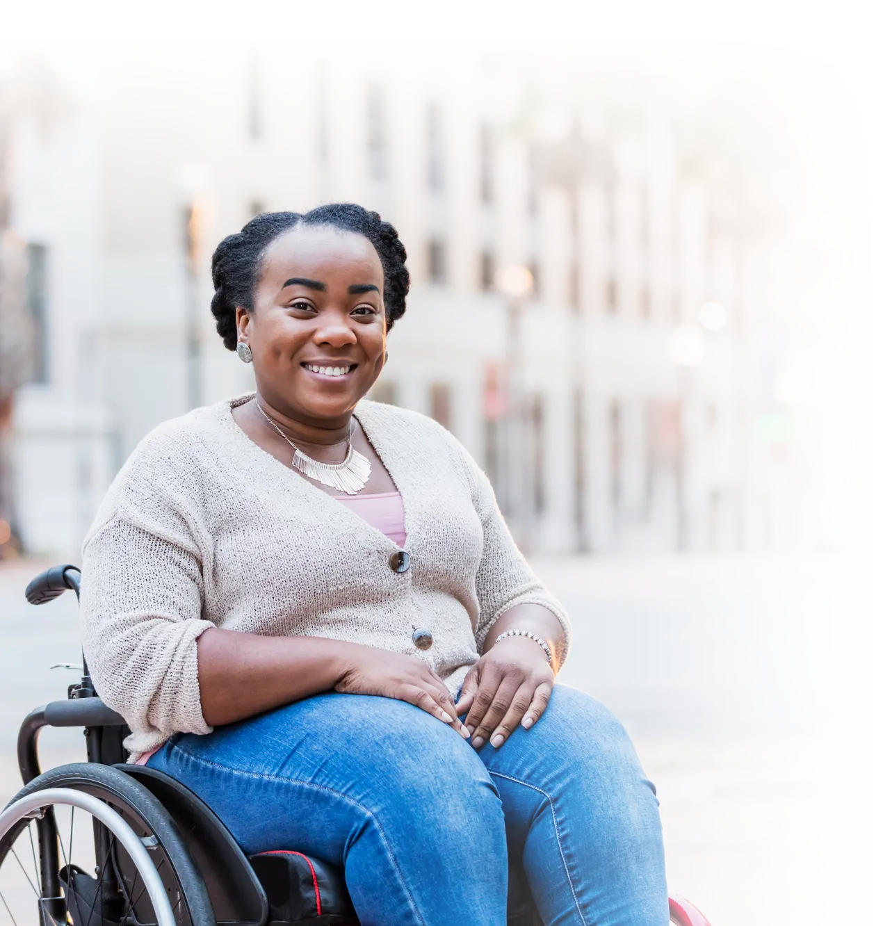 Young woman chair-user, smiling while outside on the city sidewalk.